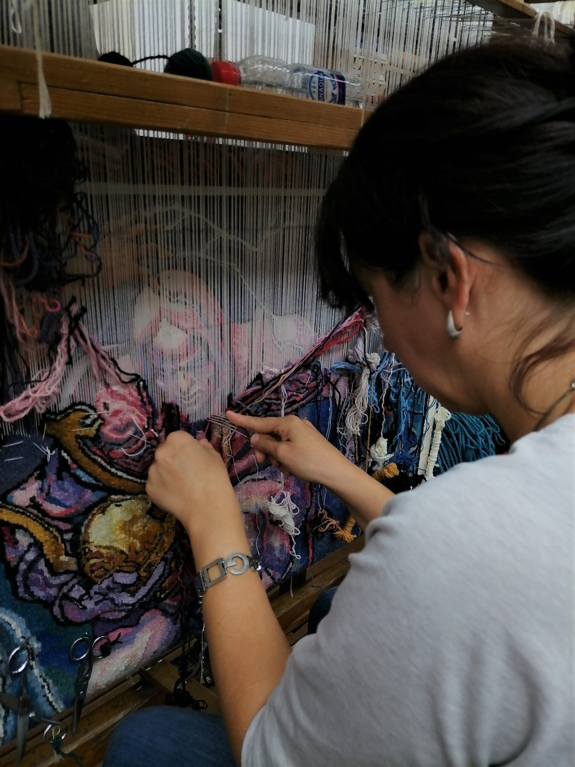 Ženska nit - žena koja radi tapiseriju na kojoj se vidi deo rada na kojem je super-heroj