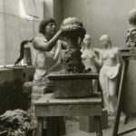 Ila Kofler, žena koja vaja vistu, u pozadini se vide razna vajarska dela, ženske figure